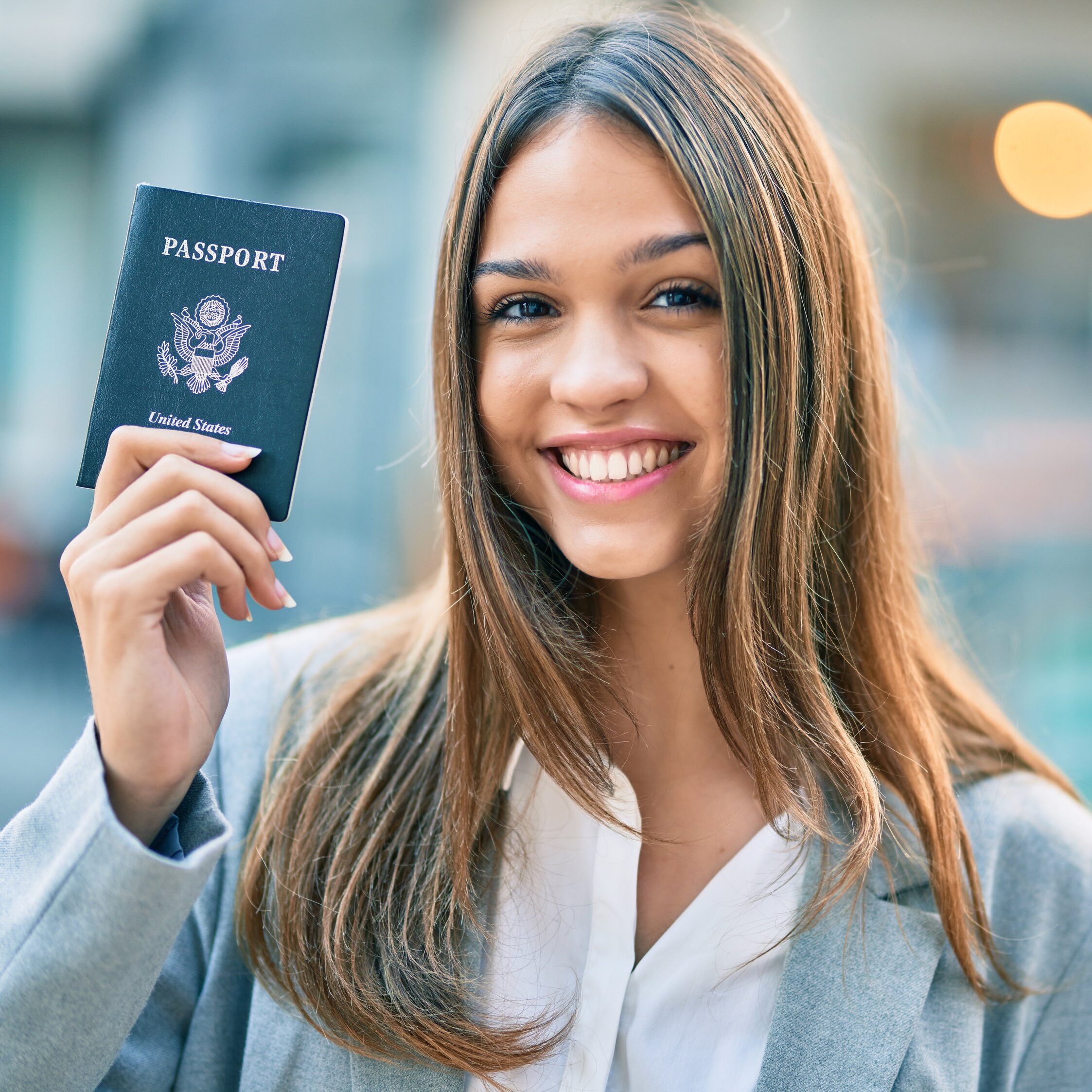 Young latin businesswoman smiling happy holding united states passport at the city.